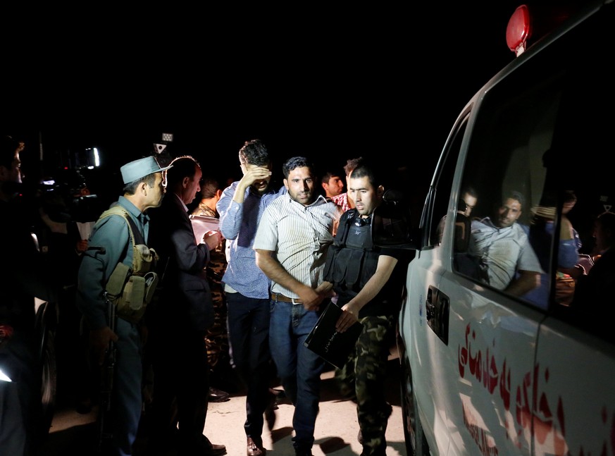 Afghan men walk towards an ambulance after they were rescued from the site of an attack at American University of Afghanistan in Kabul, Afghanistan August 24, 2016. REUTERS/Mohammad Ismail TPX IMAGES  ...