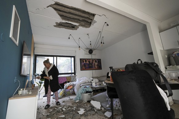 An Israeli woman inspects damage to her house hit by a rocket fired from the Gaza Strip, in Sderot, southern Israel, Friday, April 7, 2023. Israel conducted rare airstrikes in Lebanon on Friday, a sha ...