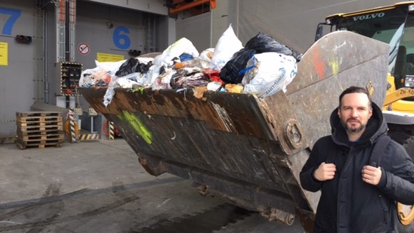 Reporter Felix Burch vor der Baggerschaufel mit 700 Kilogramm Abfall – der durchschnittlichen Menge, die jeder Schweizer pro Jahr verursacht.&nbsp;
