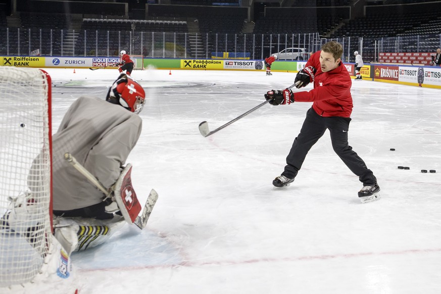 Peter Mettler, right, goaltender coach of Switzerland national ice hockey team, shoots a puck against Switzerland&#039;s goaltender Leonardo Genoni, left, during a Swiss team training optional session ...