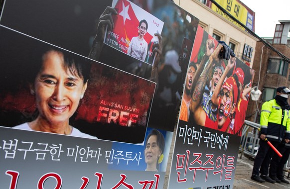 epa08988180 A South Korean protester holds up banners as police officials stand guard during a protest against the Myanmar military coup, near the Myanmar Embassy in Seoul, South Korea, 05 February 20 ...