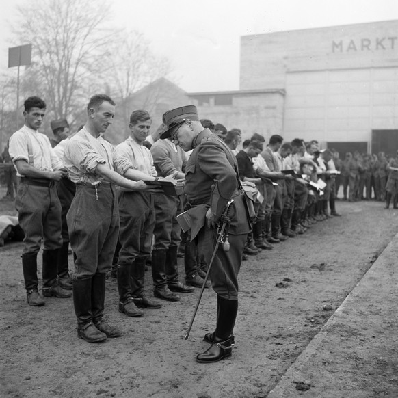 Kavalleriesoldaten der Schweizer Armee stehen am fruehen Morgen bei der Antrittsmusterung in Reih und Glied und weisen einem Offizier das Dienstbuechlein und die sauber gewaschenen Haende vor, aufgeno ...
