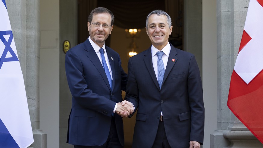 Swiss Federal President Ignazio Cassis, center, and Israel&#039;s President Isaac Herzog, left, shake hands beside Swiss Federal Councillor Guy Parmelin, during Herzog&#039;s official visit in Kehrsat ...