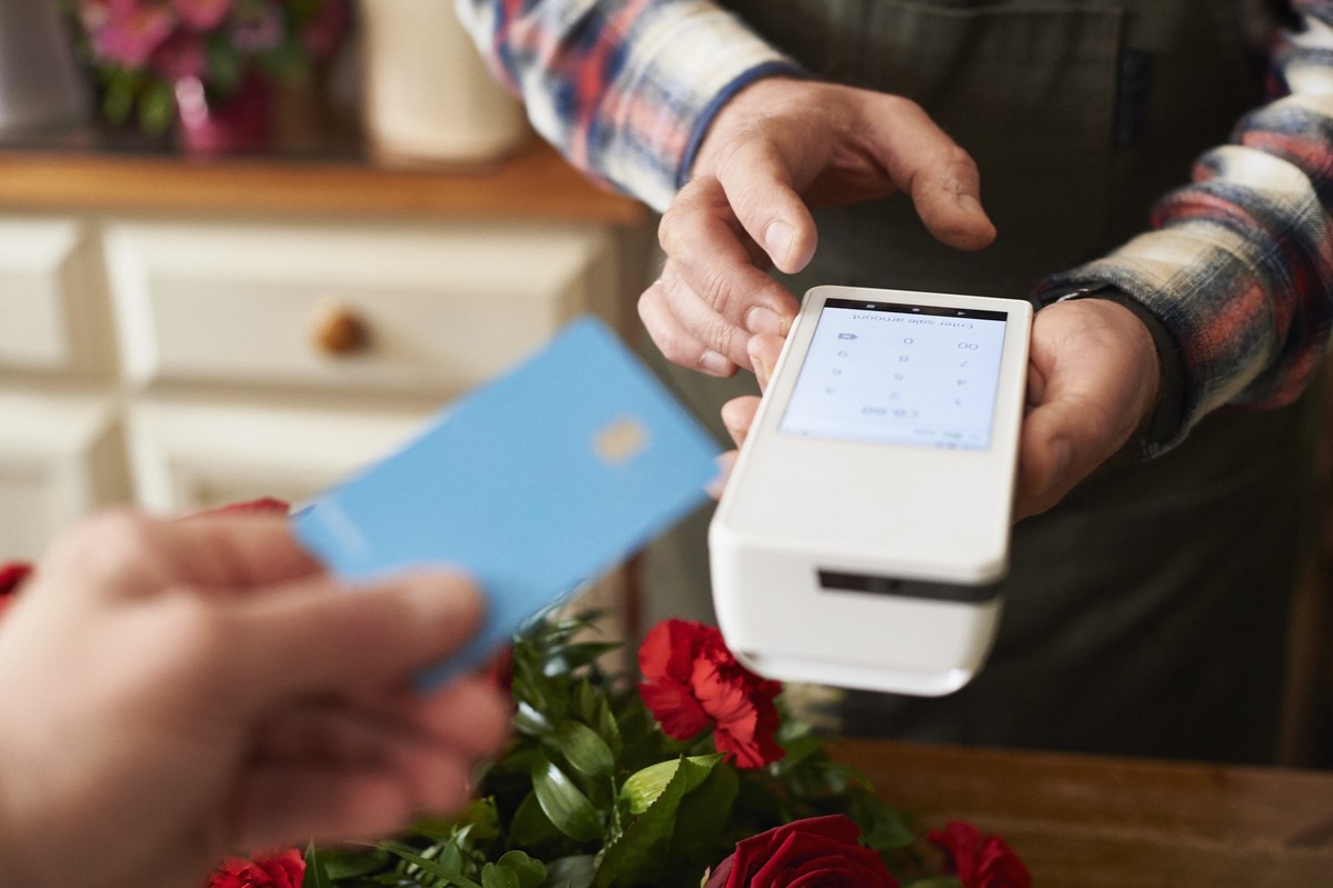A gay male florist taking payment for a flower arrangement