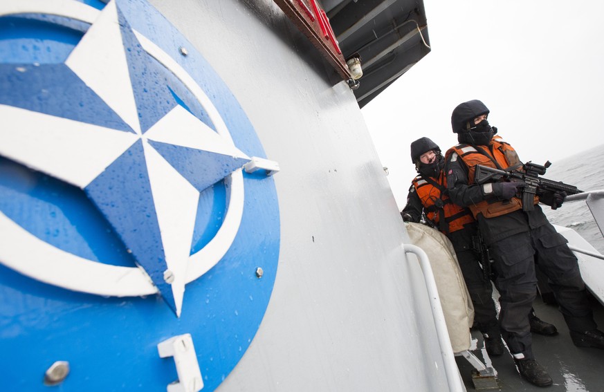Two Norwegian sailors onboard the Norwegian support vessel Valkyrien pose for photographers next to the NATO logo in the Baltic Sea along the German Coast, Wednesday, April 23, 2014. Five NATO mine-hu ...