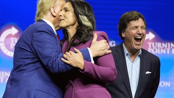 Former Democratic Rep. Tulsi Gabbard hugs Republican presidential nominee former President Donald Trump as Tucker Carlson yells during a campaign rally Wednesday, Oct. 23, 2024, in Duluth, Ga. (AP Pho ...
