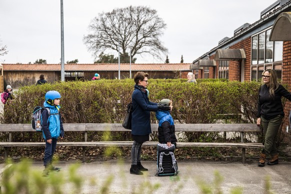 epa08363855 Parents with their children stand in queue waiting to get inside Stengaard School in Lyngby, Denmark, 15 April 2020. Nurseries, kindergardens and schools reopen in Denmark after a month-lo ...