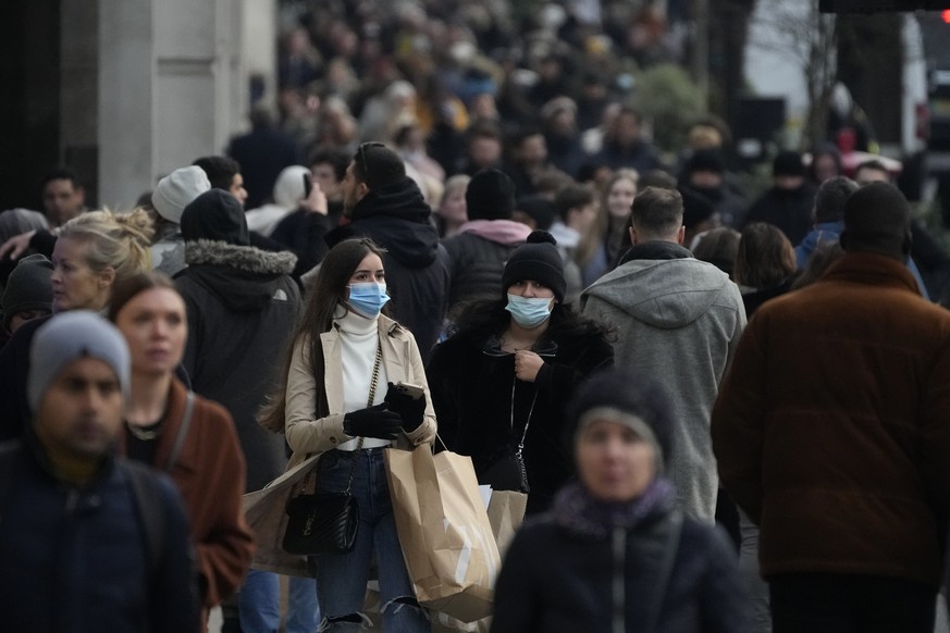 People walk with shopping bags on Regent Street in London, Monday, Nov. 29, 2021. Countries around the world slammed their doors shut again to try to keep the new omicron variant at bay Monday, even a ...