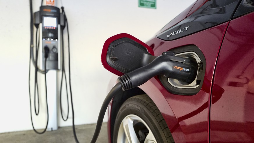 FILE - A Chevrolet Volt hybrid car is seen charging at a ChargePoint charging station at a parking garage in Los Angeles, Oct. 17, 2018. Sixteen states across the country that have tied their vehicle  ...