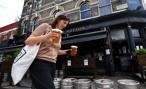 epa08510902 A customer purchases take away beers at a pub in London, Britain, 26 June 2020. Temperatures of 30C plus have brought people to public spaces as Britain continues to ease its lockdown. Bri ...
