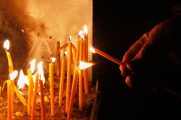 A man lights a candle to commemorate the victims of the deadly fire in a bar in Crans-Montana, Switzerland, during a vigil in Kocani, North Macedonia, on Saturday, Jan. 10, 2026. (AP Photo/Boris Grdan ...