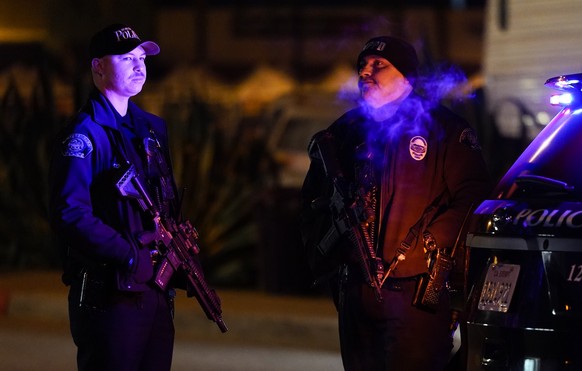 Two police officers stand guard near a scene where a shooting took place in Monterey Park, Calif., Sunday, Jan. 22, 2023. Nine people were killed in a mass shooting late Saturday in a city east of Los ...
