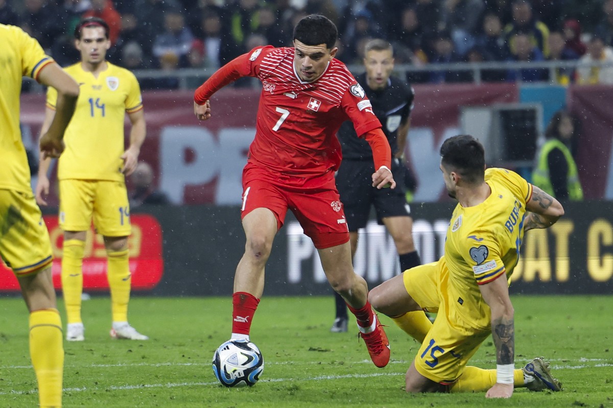 Switzerland's Zeki Amdouni, center, and Romania's Andrei Burca in action during the UEFA Euro 2024 qualifying group I soccer match between Romania and Switzerland at the National Arena stadi ...