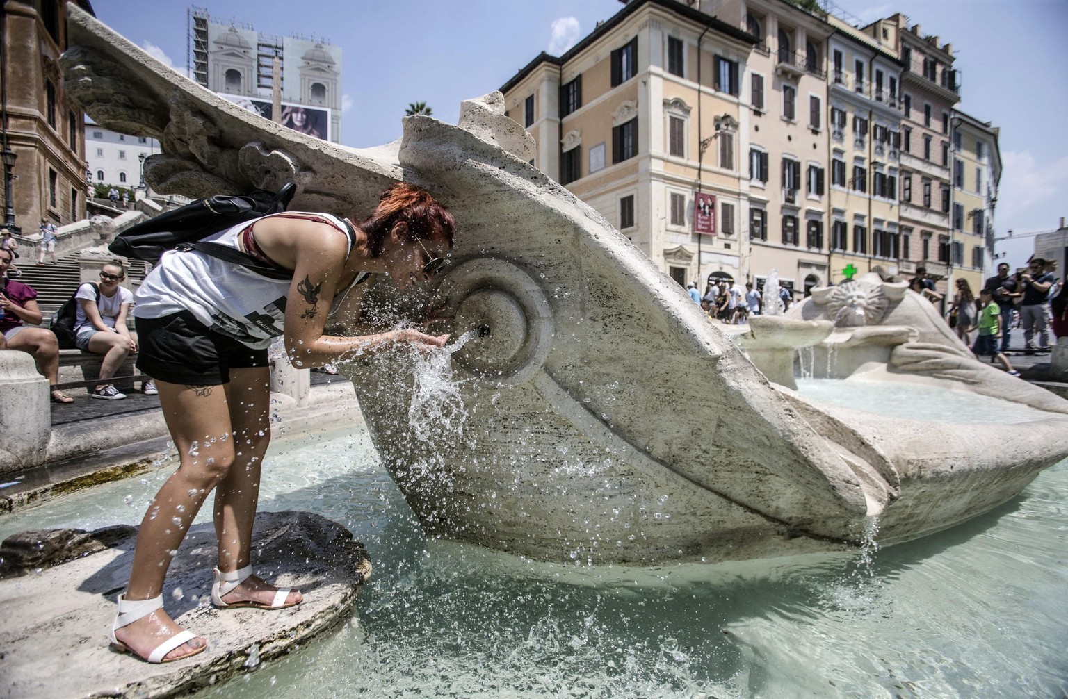 Touristin in Rom sucht Abkühlung bei einem Brunnen.