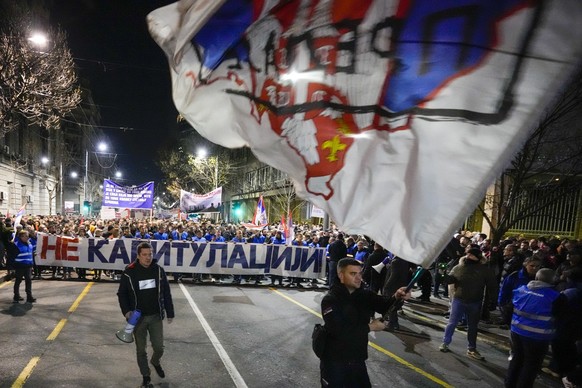 People hold a banner reading: &quot;No to capitulation&quot; as they march during a protest against the Serbian authorities and French-German plan for the resolution of Kosovo in Belgrade, Serbia, Fri ...