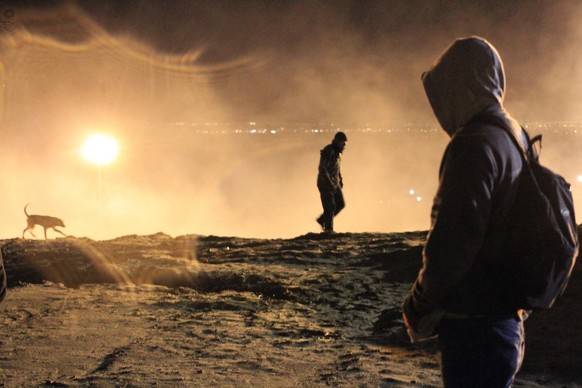 epa07257343 Central Americans try to avoid tear gas used by US border police agents during an attempt to cross the border between Mexico and the United States, in Tijuana, Mexico, early 01 January 201 ...