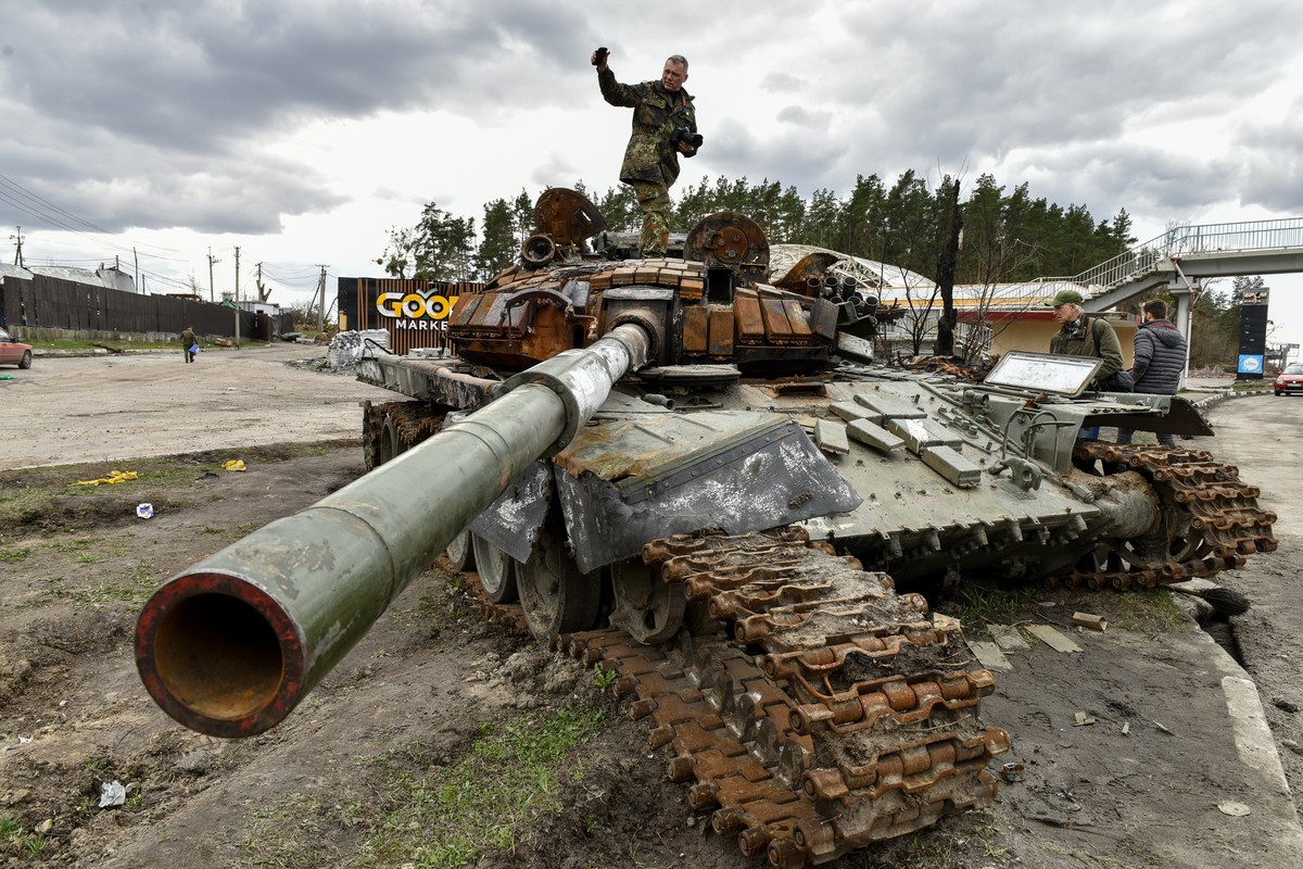 epa09884456 A man stands on destroyed russian tanks in Buzova village of Kyiv (Kiev) area, Ukraine, 11 April 2022. On 24 February, Russian troops had entered Ukrainian territory in what the Russian pr ...