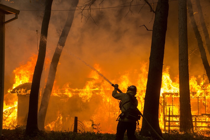 epaselect epa07154463 A CalFire firefighter attempts to cool down the side of a home in the Paradise Pines neighborhood of Magalia as the Camp Fire continues to burn out of control through the region, ...