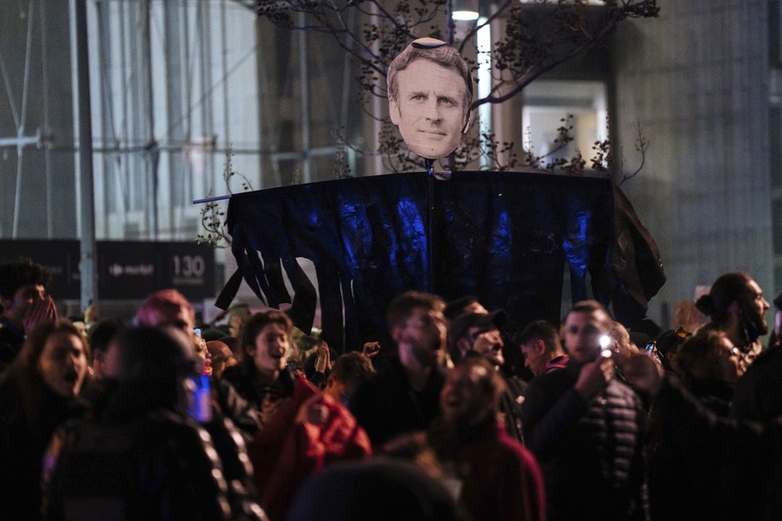 Protesters hold a banner with Emmanuel Macron&#039;s face during a protest in Paris, Saturday, March 18, 2023. A smattering of protests against President Macron?s plan to raise France&#039;s retiremen ...