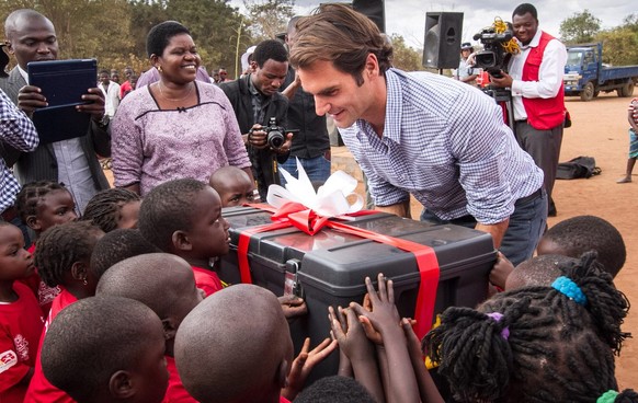 epa04854275 Swiss tennis player Roger Federer provides a box of gifts to school children during the ceremony in Lilongwe, Malawi, 20 July 2015. The Roger Federer Foundation is a community based care f ...