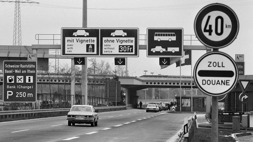 AM 26. FEBRUAR 1984 WIRD IN DER SCHWEIZ DIE AUTOBAHNVIGNETTE EINGEFUEHRT. ZUM 30. JAHRESTAG STELLEN WIR IHNEN FOLGENDES BILD ZU VERFUEGUNG ---- Beim Zoll bei Weil am Rhein bei Basel weisen Tafeln die  ...