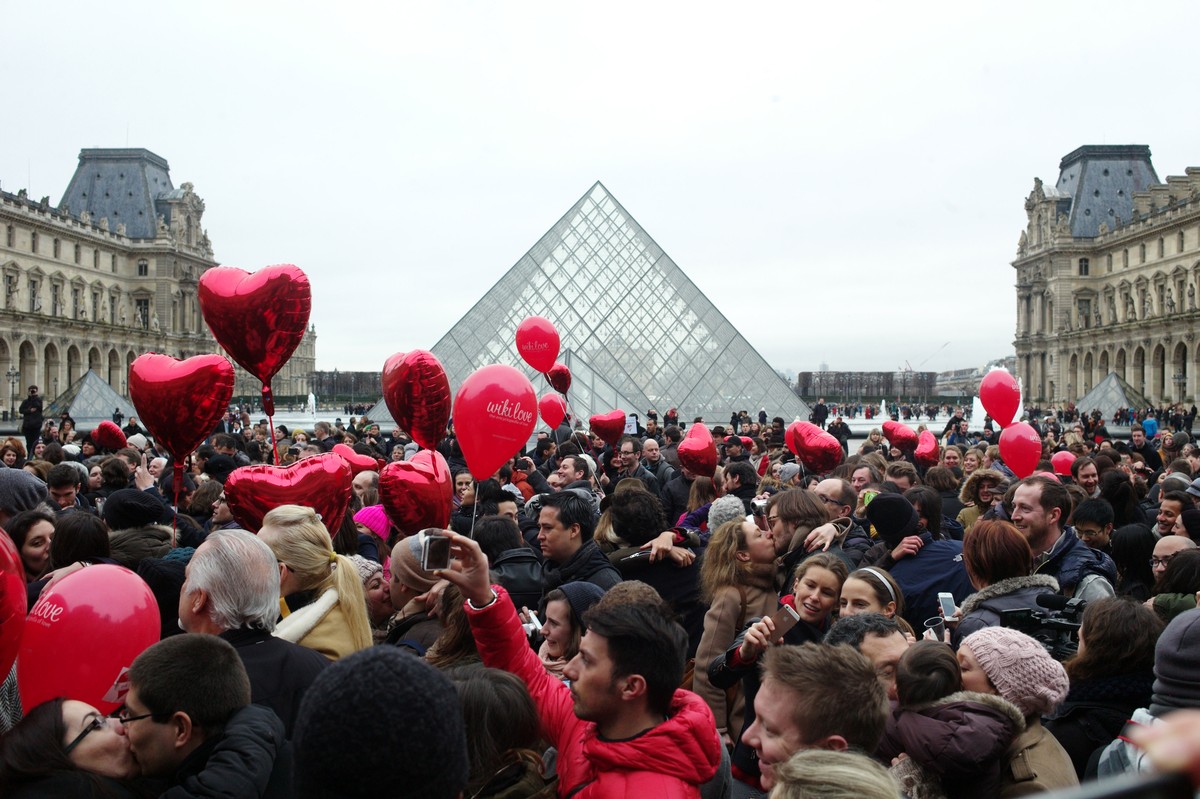 Couples share a kiss during a kissing flashmob in celebration of Valentine's Day, in front of the Pyramid at the Louvre Museum, in Paris, Friday, Feb. 14, 2014. Valentine's Day is observed o ...