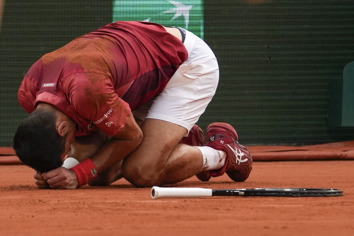 Two ball kids come to the aid of Serbia's Novak Djokovic after he slipped and fell during his fourth round match of the French Open tennis tournament against Argentina's Francisco Cerundolo  ...