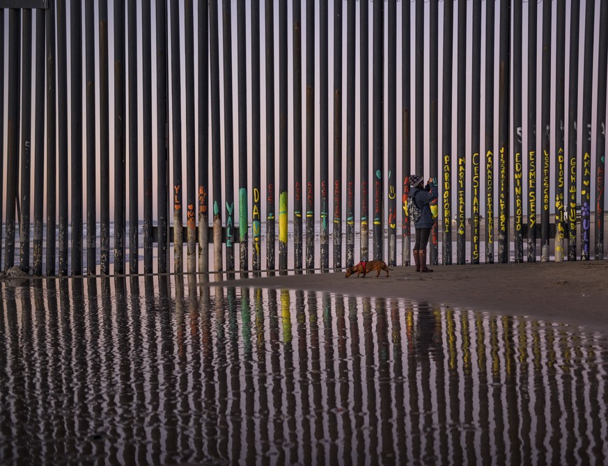 A woman takes a snapshot by the border fence between San Diego, Calif., and Tijuana, as seen from Mexico, Thursday, Jan. 3, 2019. Discouraged by the long wait to apply for asylum through official port ...