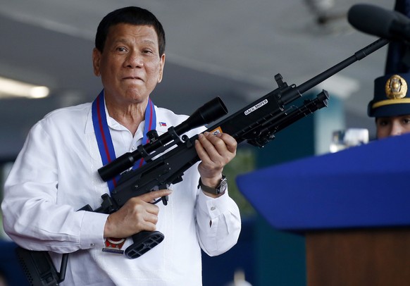 FILE - Philippine President Rodrigo Duterte jokes to photographers as he holds an Israeli-made Galil rifle at Camp Crame in suburban Quezon city northeast of Manila, Philippines on April 19, 2018. An  ...