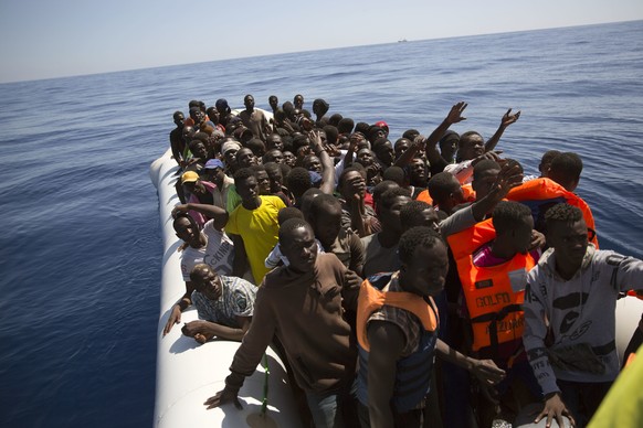 Migrants and refugees wait to receive life vests from Spanish NGO Proactiva Open Arms workers, after being located out of control sailing on a rubber boat in the Mediterranean Sea, about 18 miles nort ...