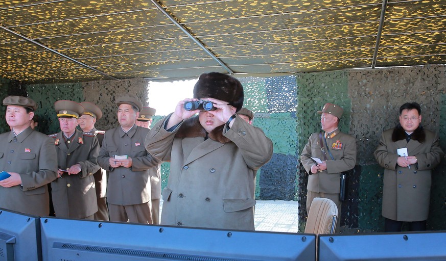 epa05226506 A picture made available by the North Korean Central News Agency (KCNA) on 23 March 2016 shows North Korean leader Kim Jong-un watching a test-fire of a new large-caliber multiple rocket l ...