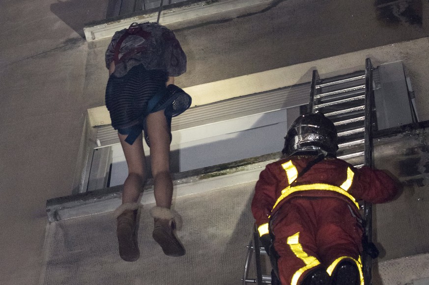 In this image provided on Tuesday, Feb. 5, 2019 by the Brigade de Sapeurs-Pompiers de Paris (Paris Fire Brigade) firefighters use a rope to evacuate a resident after a fire engulfed an apartment build ...