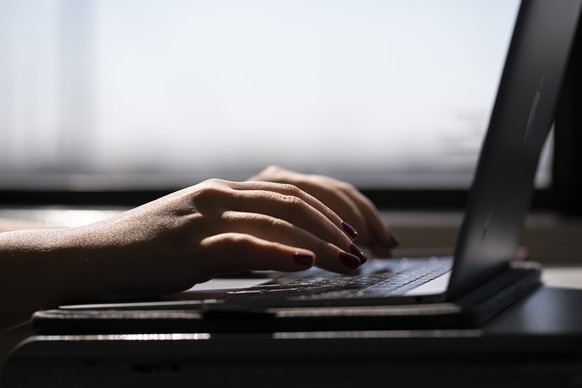 FILE - This May 18, 2021, photo shows a woman typing on a laptop on a train in New Jersey. Major websites were down for Thursday in what appeared to be a brief but widespread outage. Major websites we ...