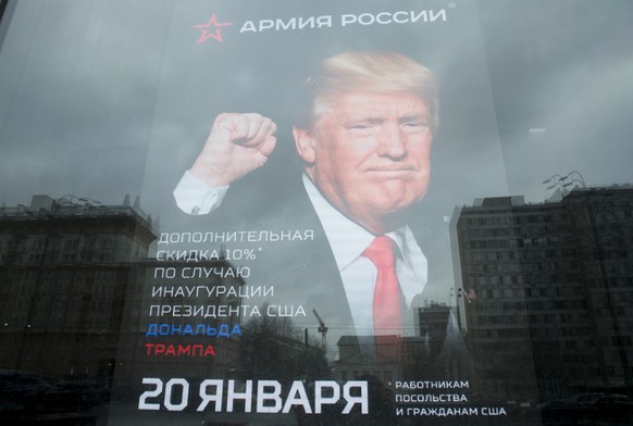 The U.S. Embassy building is reflected in a window of a Russian military outerwear shop &quot;Armia Rossii&quot; (Russian Army) displaying a poster of Donald Trump, in downtown Moscow, Russia, Friday, ...