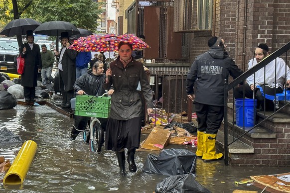 Pedestrians walk along a flooded sidewalk, Friday, Sept. 29, 2023, in the Brooklyn borough of New York. A potent rush-hour rainstorm has swamped the New York metropolitan area. The deluge Friday shut  ...