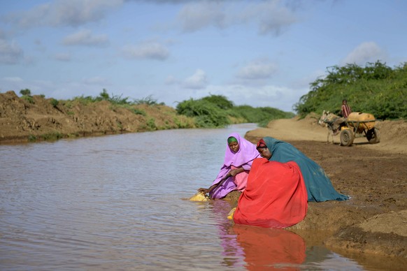Frauen schöpfen Wasser aus einem Fluss in Somalia.