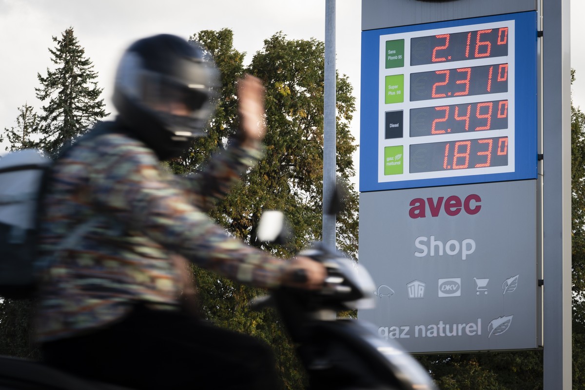 Une scooter passe devant une station-service avec les prix de l'essence (ici le sans plond 95 a 2.16 chf/L, super plus 98 a 2.31 chf/L, Diesel a 2.49 chf/L, et gaz naturel a 1.83 chf/L), le vendr ...