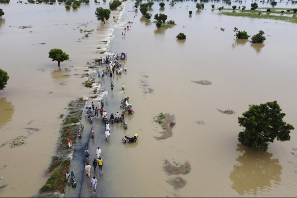 People walk through floodwaters after heavy rainfall in Hadeja, Nigeria, Monday, Sept 19, 2022. Elections, coups, disease outbreaks and extreme weather are some of the main events that occurred across ...