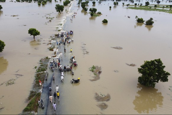 People walk through floods after heavy rains in Hadeja, Nigeria, Monday, September 19, 2022. Elections, coups, disease outbreaks and extreme weather are some of the major events that took place in…