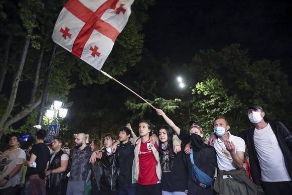 Demonstrators wave a Georgian national flag standing in front of police block during an opposition protest against a bill near the Parliament building in Tbilisi, Georgia, on Thursday, May 2, 2024. Pr ...