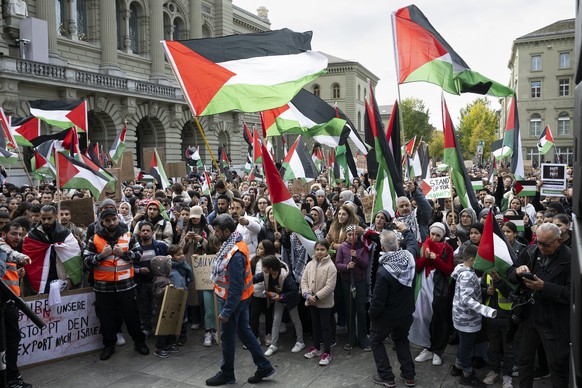 epa10944941 Protesters hold Palestinian flags and placards during an authorized rally in solidarity with Palestine, at the Federal square, in Bern, Scwitzerland 28 October 2023. Thousands of Israelis  ...