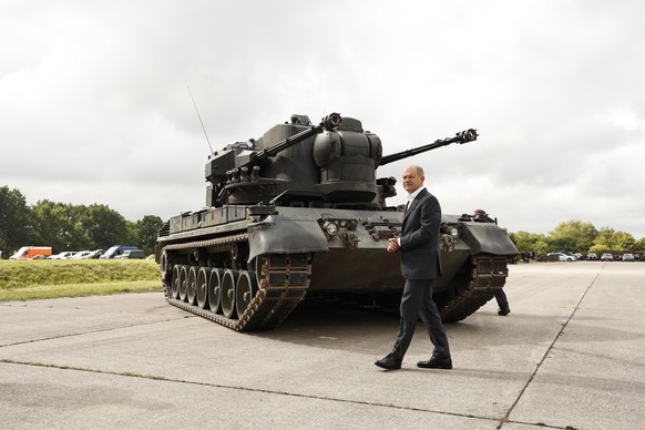 epa10137718 German Chancellor Olaf Scholz poses in front of an anti-aircraft gun tank Gepard during his visit to a training facility of the gunmaker Krauss-Maffei Wegmann in the military training of Putlos...