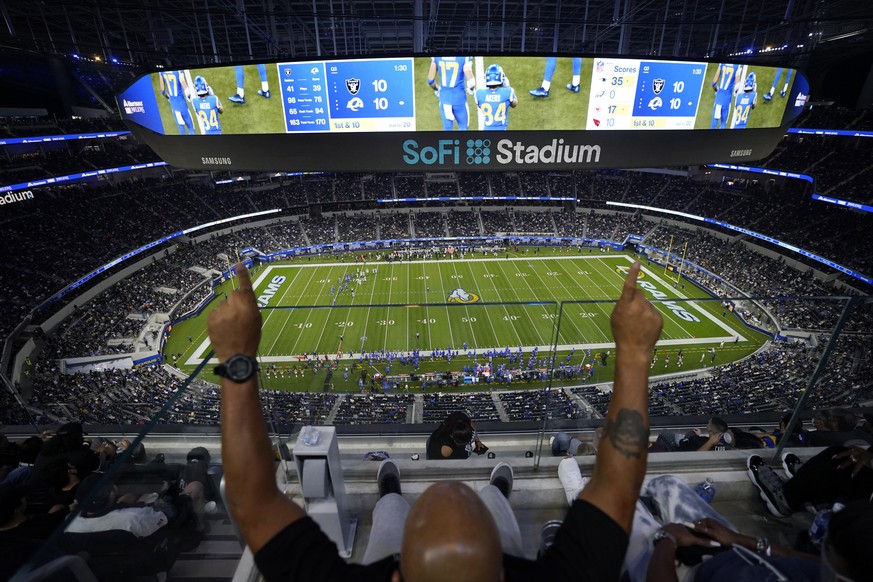 A fan cheers from the upper deck at SoFi Stadium during the second half of a preseason NFL football game between the Los Angeles Rams and the Las Vegas Raiders on Saturday, Aug. 21, 2021, in Inglewood ...
