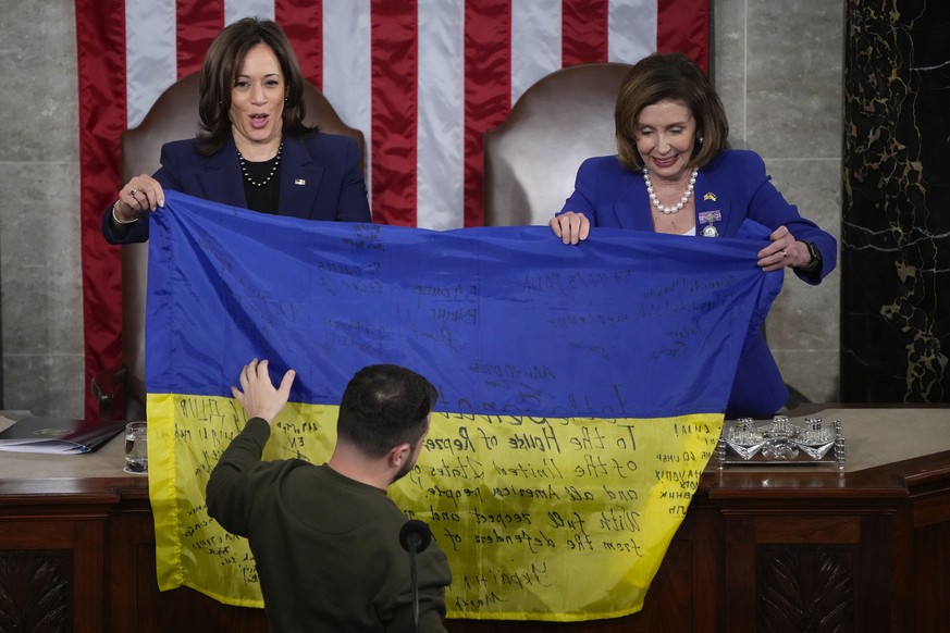 Vice President Kamala Harris and House Speaker Nancy Pelosi of California, right, react as Ukrainian President Volodymyr Zelenskyy hands lawmakers a Ukrainian flag autographed by frontline troops…
