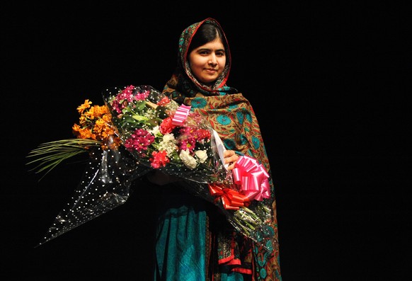 FILE - In this Friday, Oct. 10, 2014, file photo, Malala Yousafzai poses with a bouquet after speaking during a media conference at the Library of Birmingham, in Birmingham, England, after she was nam ...