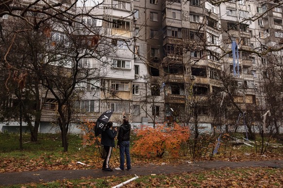 epa10327782 People look at a damaged residential building after the recent Russian attack, in Kherson, southern Ukraine, 25 November 2022. Russian troops for the past few days intensified the shelling ...