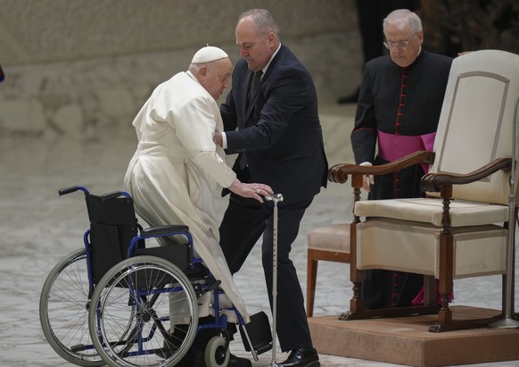 Pope Francis is helped by his assistant Piergiorgio Zanetti as he arrives for his weekly general audience in the Paul VI Hall, at the Vatican, Wednesday, Feb. 12, 2025. (AP Photo/Alessandra Tarantino) ...