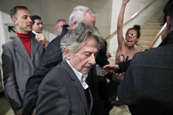 epa06298892 An activist (R) from the Ukrainian feminist group Femen shouts slogan as Polish-French director Roman Polanski (C) as he arrives at La Cinematheque for the launch of his retrospective in P ...