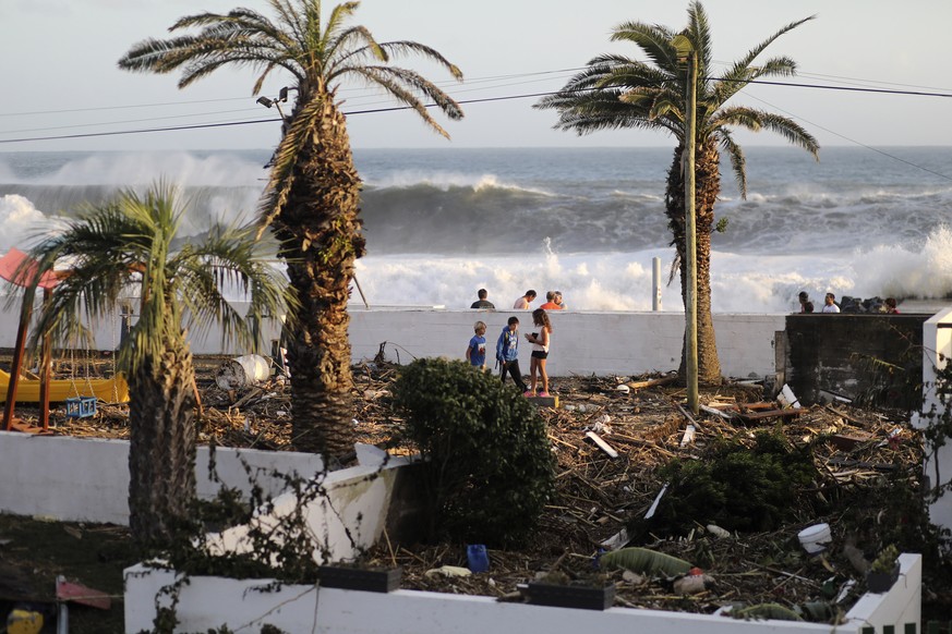 Children walk in a playground littered with debris carried by wind and waves in the village of Feteira, outside Horta, in the Portuguese island of Faial, Wednesday, Oct. 2, 2019. Hurricane Lorenzo pow ...