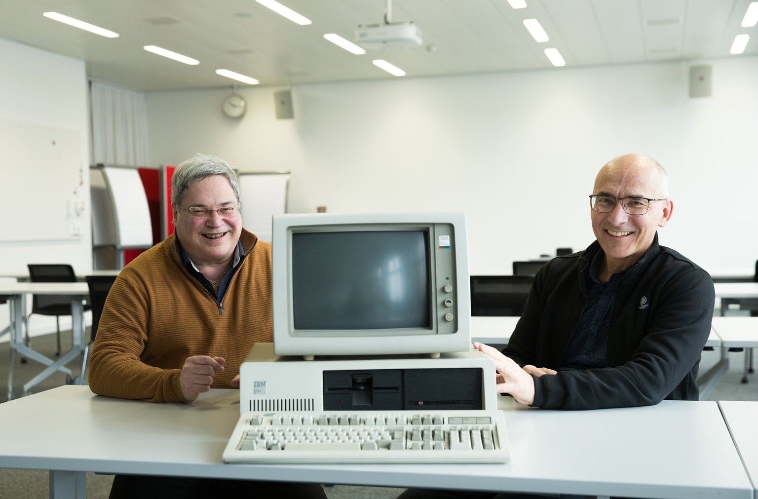 Markus Stucki (links), Cybersecurity-Spezialist der Mobiliar, übergibt Thomas Brunner (rechts), Leiter Infrastruktur Facility Management, einen IBM Personal Computer XT (Typ 5160).